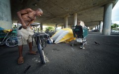 Oliver (only first name given) adjusts his bicycle near his tent under the H1 overpass, along Harding Avenue. homeless tents. 16 july 2015. photograph Cory Lum/Civil Beat