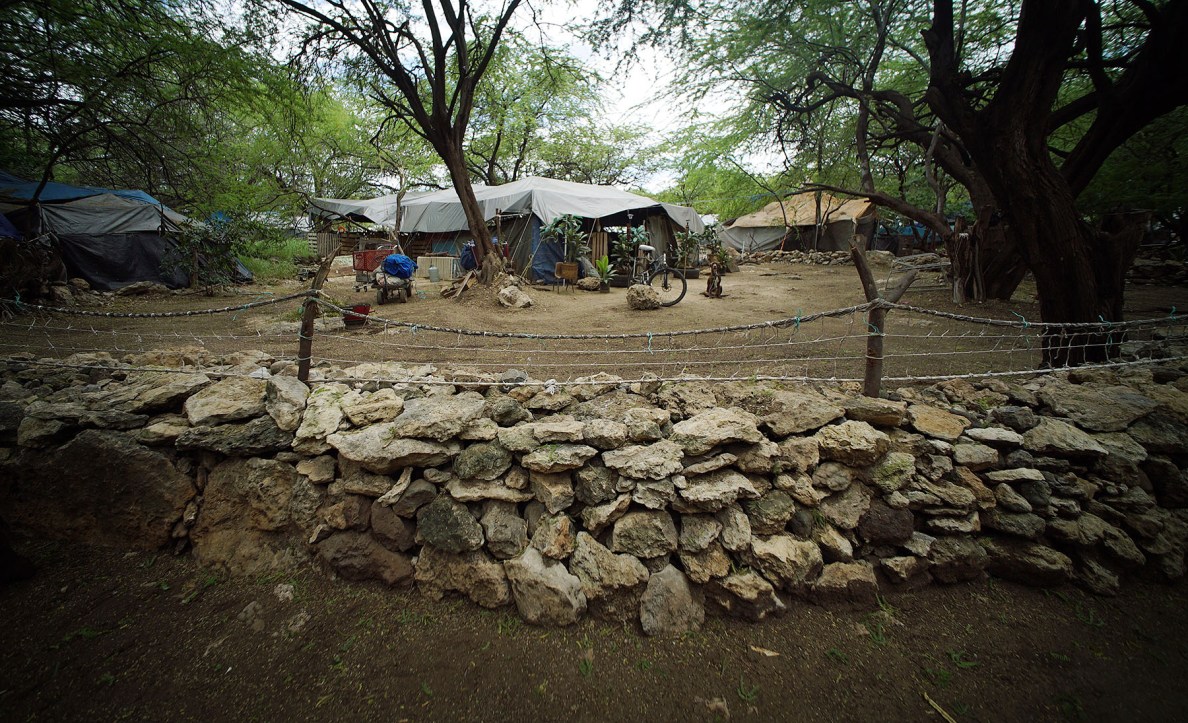 Fenced and gated entrance, surrounded by a wall of coral rock around the perimeter of this camera shy resident located inside the Waianae Boat Harbor encampment.