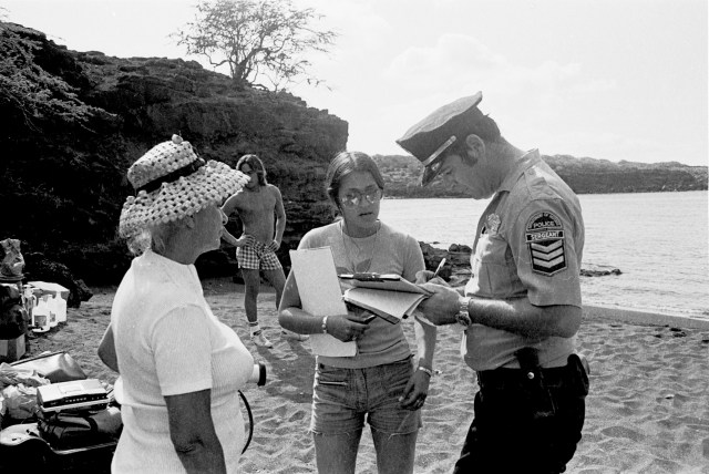 A Department of Defense police officer takes information from Karla Villalba and Ellen Miles. Kimo Aluli is in the background.