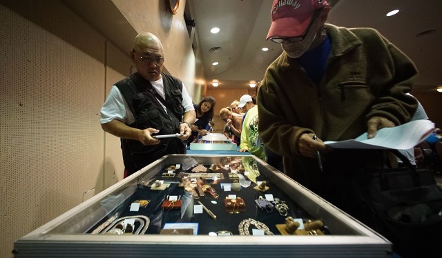 Members of the public / potential bidders view some of the jewelry and other valuables in covered containers before the AG offices' auction of forfeited property held at Neal Blaisdell Exhibition Hall. 9 april 2016.