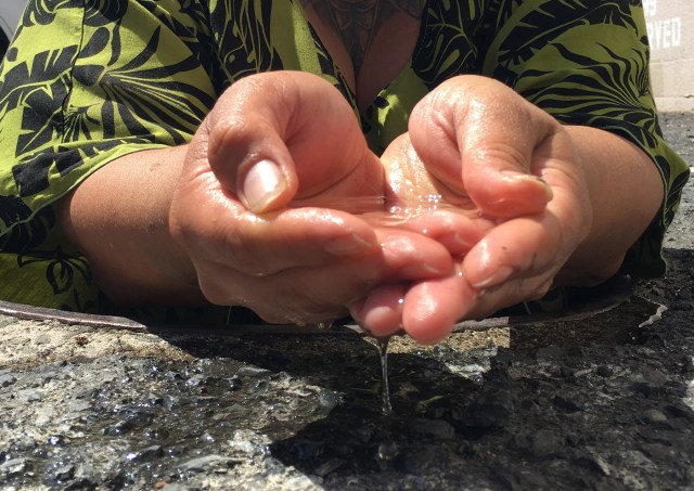 Cultural advisor Hinaleimoana Wong-Kalu holds some of the water from the underground auwai. 