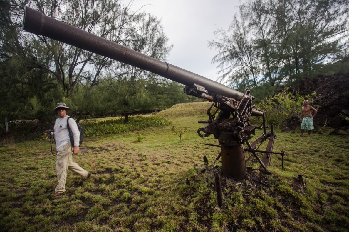 Earthjustice attorney David Henkin, who is suing the Navy, walks by a cannon on Pagan leftover from World War II. Gus Kaipat stands in the background. Kaipat is one of the former residents of Pagan who wants to live there permanently.