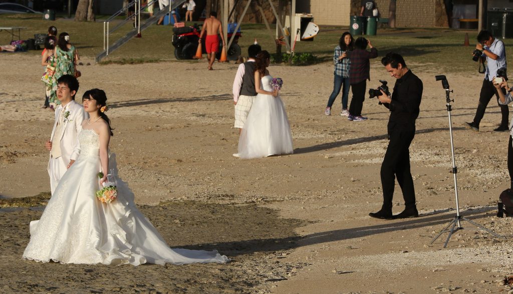 Wedding couples, both faux and possibly real pose along the Magic Island side of Ala Moana Beach Park.