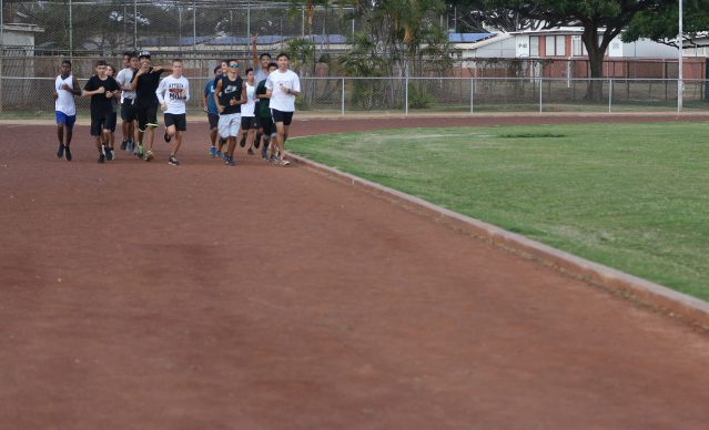 Campbell High School students run on their dirt track that encircles their grass football field.