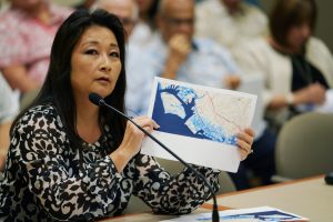 Rep Sylvia Luke holds graphic ocean inundation areas in Kakaako HART Meeting in Kapolei.