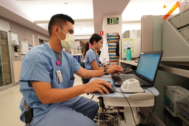 Queens Emergency Room staff work at their stations.