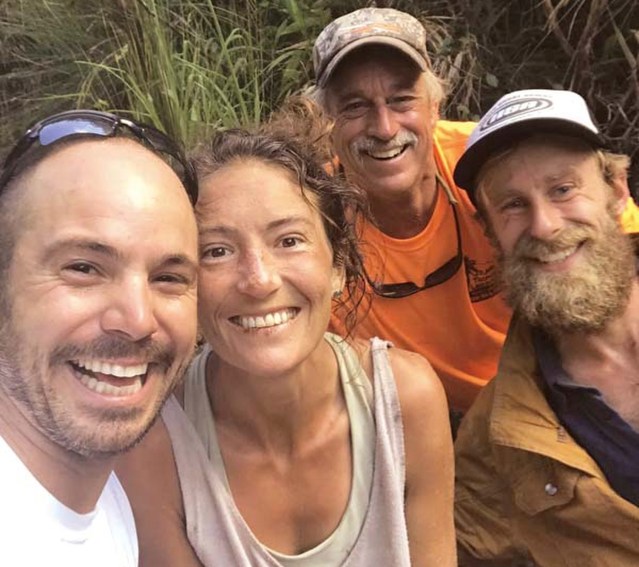 In this Friday, May 24, 2019, photo provided by Troy Jeffrey Helmer, resident Amanda Eller, second from left, poses for a photo after being found by searchers, Javier Cantellops, far left, Helmer and Chris Berquist above the Kailua reservoir in East Maui, Hawaii, on Friday afternoon. The men spotted Eller from a helicopter and went down to retrieve her. She was taken to the hospital and was in good spirits, her family said. Eller had been missing since May 8. (Troy Jeffrey Helmer via AP)