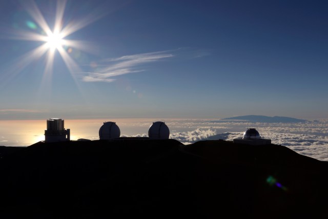 FILE - In this Sunday, July 14, 2019, file photo, the sun sets behind telescopes at the summit of Mauna Kea. Scientists are expected to explore fundamental questions about our universe when they use a giant new telescope planned for the summit of Hawaii’s tallest mountain. That includes whether there’s life outside our solar system and how stars and galaxies formed in the earliest years of the universe. But some Native Hawaiians don’t want the Thirty Meter Telescope to be built at Mauna Kea’s summit, saying it will further harm a place they consider sacred. (AP Photo/Caleb Jones, File)
