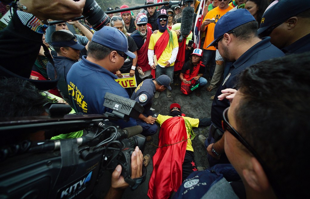Mauna Kea supporters right hold their line as left, DLNR law enforcement officers tell them to clear the road to allow their vehicles to make the ascent to the summit. One demonstrator decided not to move and instead laid on the ground only to be arrested within minutes. 24 june 2015. photograph Cory Lum/Civil Beat
