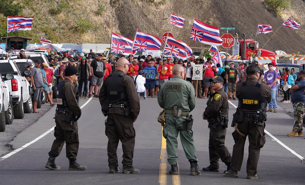 TMT demonstrators chant as State Sheriffs stand on Mauna Kea Access Road. Demonstrators were angry about a gate installed along Mauna Kea Access Road.