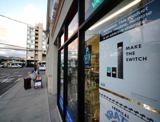 Vape Hawaii Juul advertisement in window ‘Make the Switch’ with warning, ‘This item contains nicotine. Nicotine is a addictive chemical’.