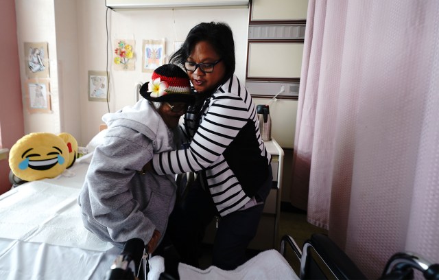 Wahiawa General Hospital Long Term Care resident 84 year old Rosita Yadao gets a lift from Leilanie Sacro.