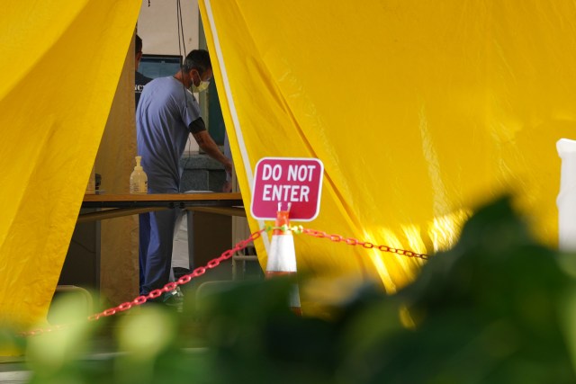 Queen’s Hospital staff wears mask inside the tent located near the entrance to the Emergency Room.