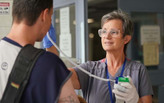 RN Elizabeth Glenn uses thermometer at IHS, she later screened guest with questions about his previous travel itinerary.
