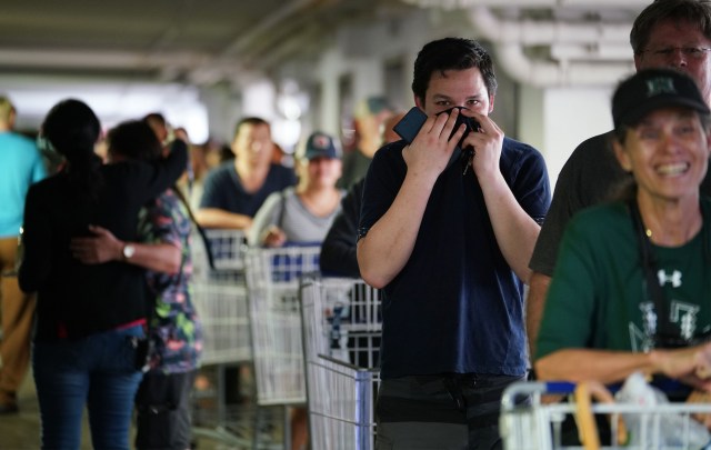 Jay Nordyke holds his shirt over his face wil standing in line with his dad, Thomas Nordyke in the parking lot of Sams Club. The lines snaked from the entrance all the way to the far side of the parking lot.