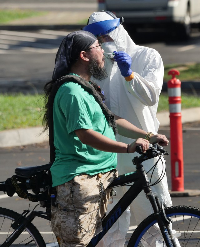 Michael Yoshida has his nose swabbed for the COVID-19 test after riding his bike to the drive through test site set-up at the Kaka'ako Waterfront Park in Honolulu, Sunday, March 29, 2020 in Honolulu, HI. (Ronen Zilberman photo Civil Beat)