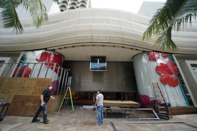Workers board up entrance of DFS Galleria Waikiki along Kalakaua Avenue during COVID-19 Coronavirus pandemic. April 13, 2020