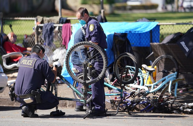 HPD officers confiscate bicycles from encampment near Moiliili Field during Coronavirus pandemic. April 17, 2020.