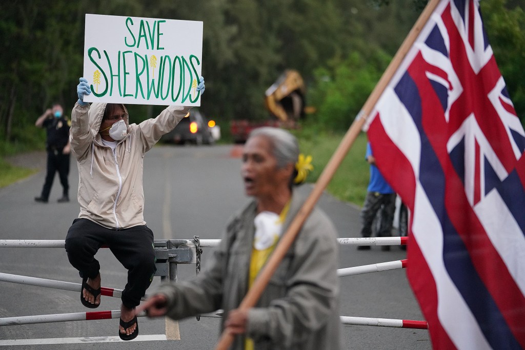 Kalokahi Kauka holds his sign after a large truck with heavy machinery drove into the park area near Sherwood Forest. April 6, 2020.