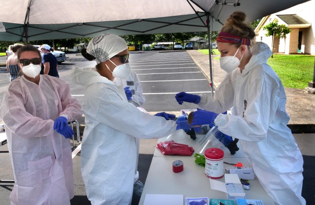 Volunteers from the the COVID Command Mobile Unit, of the Premier Medical Group Hawaii, help each other suit up in PPE gear so they can test those who show up for the free drive through testing event in Wahiwa,HI on Wednesday, April 22, 2020. (Ronen Zilberman photo Civil Beat)