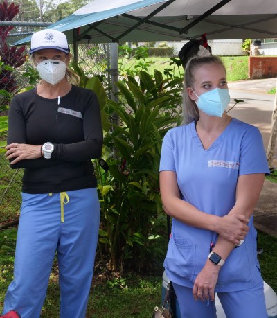 Unpaid volunteers Chris Tomlinson, a Honolulu hospital nurse (left) and Stephany Hall, a nurse (right) wait for people to arrive so they can start the screening process for COVID-19 testing during the free drive through event in Wahaiwa, HI, on Wednesday, April 22, 2020. (Ronen Zilberman photo Civil Beat)