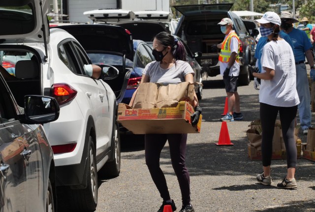 A volunteer loads a box of groceries into the trunk of a car at the big food distribution event held at Aloha Stadium in Honolulu, HI, Wednesday, May 6, 2020. The city of Honolulu, Hawaii Foodbank, and Hawaii Community Foundation collaborated to put on the event providing food for approximately 4,000 Oahu households. (Ronen Zilberman photo Civil Beat)