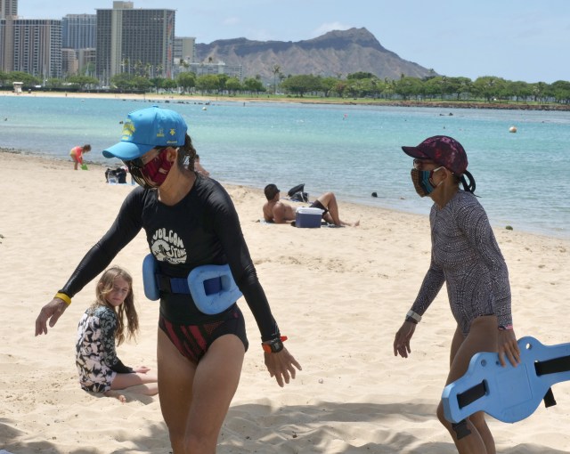 Judith Inazu (left) and Lorie Young (right) head to the showers, after finishing their aqua jogging class in the water, at Ala Moana Beach Park, Thursday, May 28, 2020, in Honolulu, HI. The ladies are some of the very few beach goes who choose to keep their masks on even while in the water. (Ronen Zilberman photo Civil Beat)