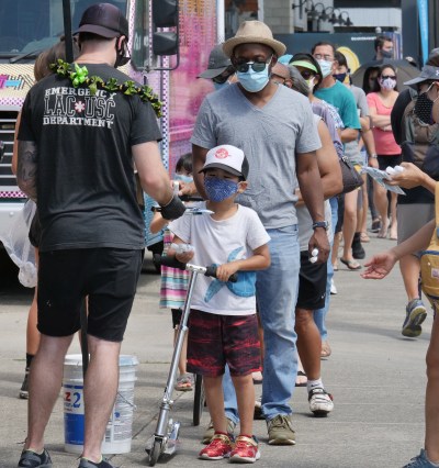 People lined the sidewalk in a snaking line around the block Friday morning to receive free disposable paper masks being distributed to the public in the Kaka'ako district of Honolulu, HI, May 1, 2020. The event was hosted by the Every1ne Hawaii group which is now focusing its community efforts to help spread awareness and best practices about managing the spread of COVID-19 moving forward. (Ronen Zilberman photo Civil Beat)