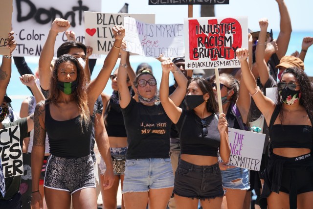 Black Lives matter Peaceful Protest supporters chant and raise their hands in a fist at the Duke Kanamoku Statue after marching from Ala Moana Beach Park.
