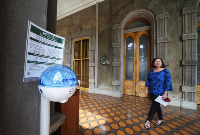 Hand sanitizer in foreground at the entrance of Iolani Palace during COVIV-19 pandemic as Paula Akana explains hew safety protocols and the opening of Iolani Palace with limited weekend hours.