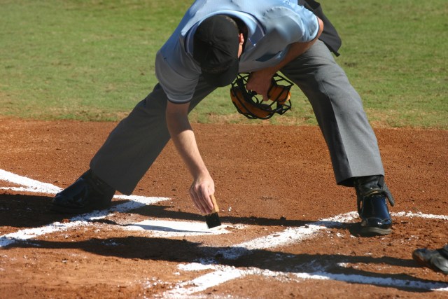 an ump sweeping off the plate