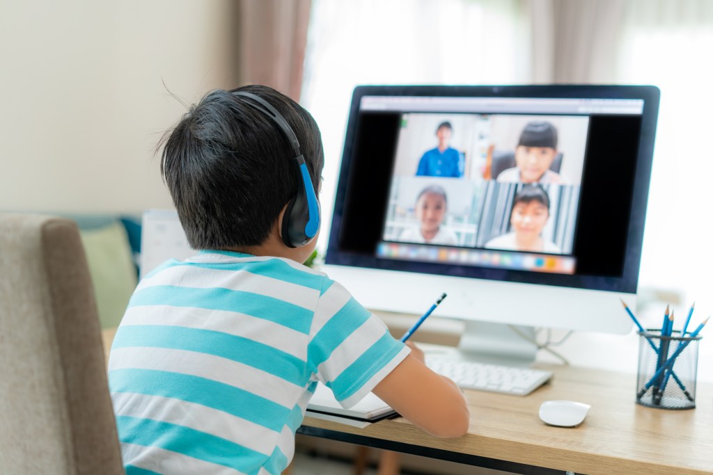 Asian boy student video conference e-learning with teacher and classmates on computer in living room at home. Homeschooling and distance learning ,online ,education and internet.
