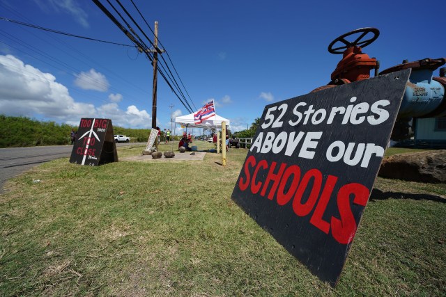 Opponents against the windmills in Kahuku hold signs along Kamehameha Highway.