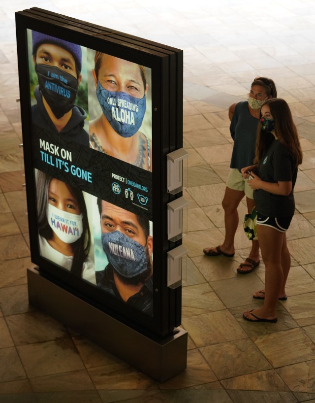Shoppers stand near an advertisement at Ala Moana Center advocating for ‘Mask On’ during COVID-19 pandemic. October 12, 2020