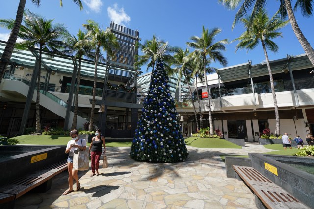 Masked customers stroll by the holiday decorations at Ala Moana Center during COVID-19 pandemic.