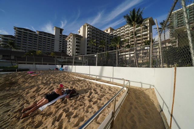 Lone sunbather fronting the fenced Halekulani Hotel during COVID-19 pandemic.