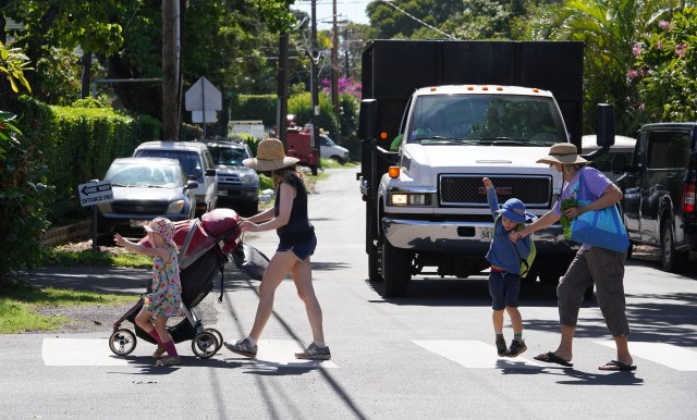 Pedestrians cross Leahi Street with cars parked along side this private road.
