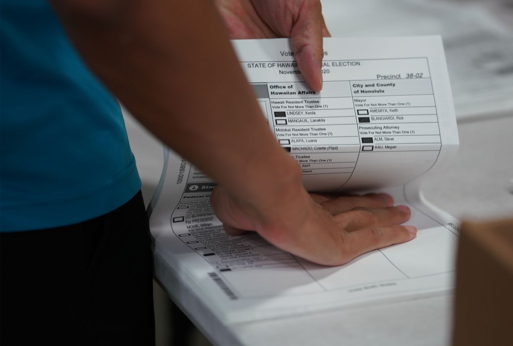 Elections officials flatten ballots before they can be scanned at the Hawaii Convention Center.