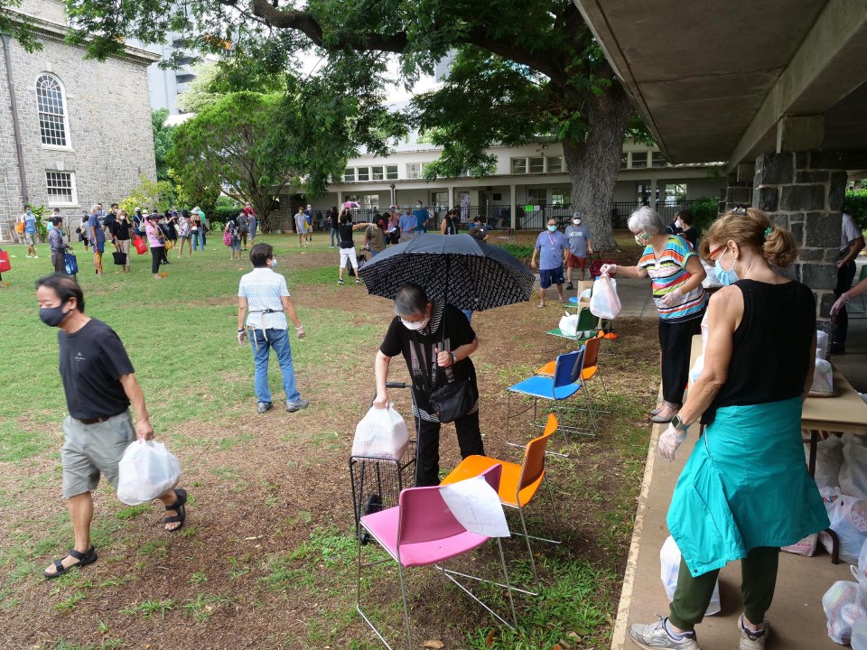 Volunteers set bags of food onto chairs to maintain social distancing with residents who arrived to pick-up the donations at the Central Union Church in Honolulu, HI, Wednesday, November 18, 2020. (Ronen Zilberman photo Civil Beat)