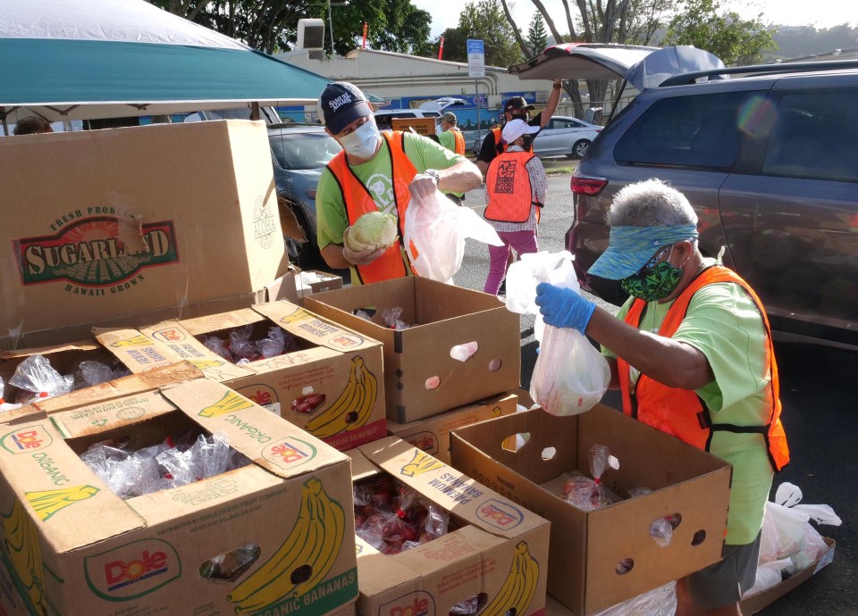Foodbank volunteers, Franz Shell (left) and Wileen Bisciano pack fresh produce into bags to be given out during a pop-up food distribution event in Kalihi Wednesday, November 11, 2020.  (Ronen Zilberman photo Civil Beat)