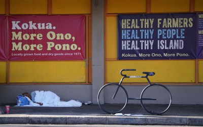 Person sleeps on sidewalk fronting Kokua Market in Moiiliili during COVID-19 pandemic. December 12, 2020