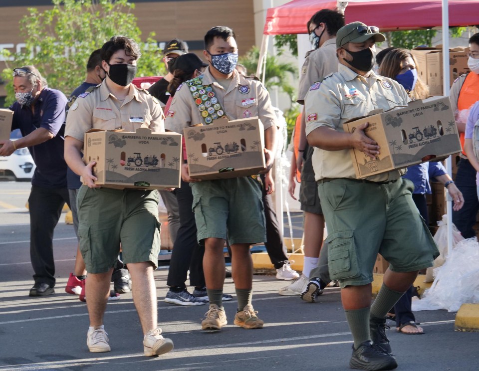 Boy Scout volunteers carry boxes of food to waiting cars, during the Feed Our Ohana Day with Aloha distribution event, at the Pearlridge Shopping Center, Saturday, December 5, 2020. Each Ohana Packs passed out to Pearl City and Aiea residents contained 20 pounds of fresh produce, eggs, milk, bread, and meats. (Ronen Zilberman photo Civil Beat)