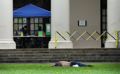 Person sleeps on the front lawn of the Hawaii State Library. January 5, 2021