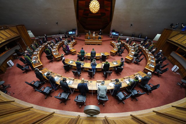 House members gather on the floor with plastic barriers between members on opening day of the 2021 legislature.