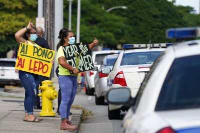 Demonstrators hold signs along Beretania Street fronting the Capitol on the opening day of the 2021 legislature.