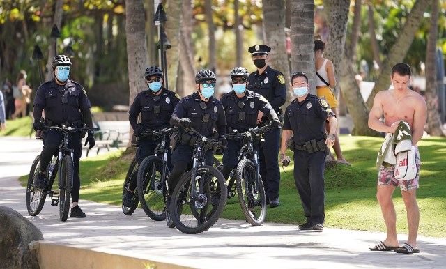 Honolulu Police Department patrols with unmasked person in foreground in Waikiki during the COVID-19 pandemic.