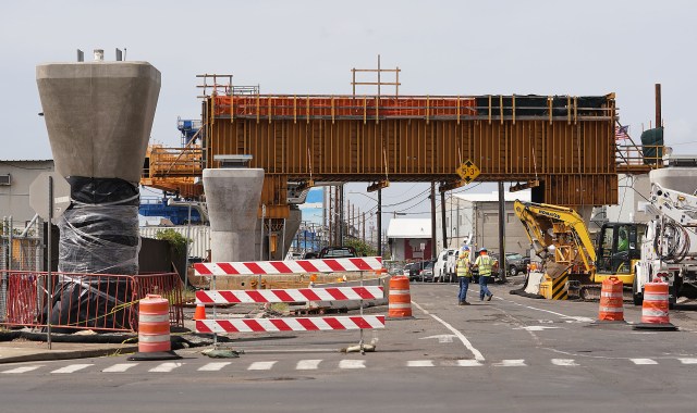 Workers walk near HART rail construction near guideway columns located on Ualena Street as rail heads towards metropolitan Honolulu.