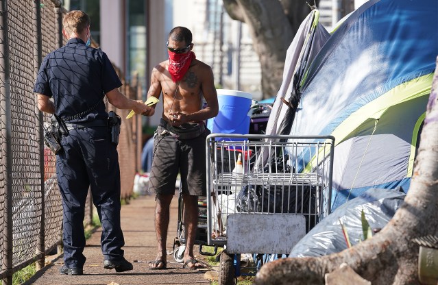 Lucky Orrukem receives a citation as HPD officers cite people living in tents along Isenberg Street adjacent to Moiliili Neighborhood Park. March 23, 2021