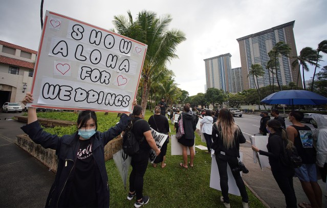 Melissa Le holds her sign in support of her sister’s wedding planner business with other wedding industry advocates fronting Honolulu Hale.