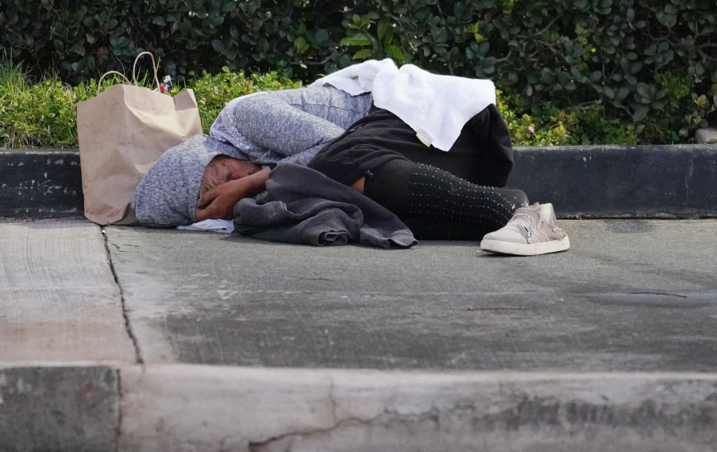 A person sleeps on the sidewalk along South King Street near the Piikoi Street intersection in the early morning hours.